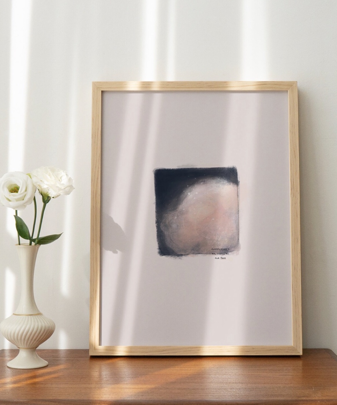 A framed Hey Little Sun art print on a sunlit shelf