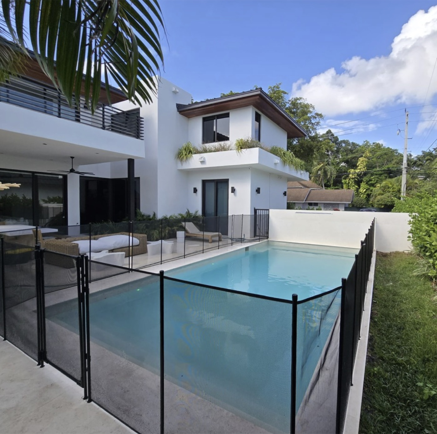 A backyard pool enclosed by a mesh pool safety fence